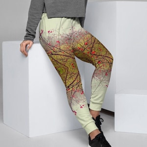 May include: A woman wearing a gray cropped sweater and light green joggers with a red and yellow floral print. The joggers have a drawstring waistband and a relaxed fit.