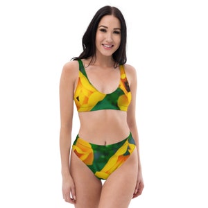 May include: A yellow and green floral print bikini top and bottom. The top has a scoop neck and the bottom is high waisted.