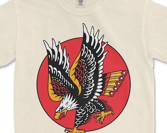 Camiseta com estampa de tatuagem de águia, design tradicional americano, cores confortáveis.