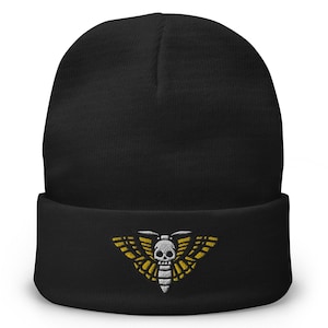 May include: Black beanie with a white skull and yellow moth embroidered on the front.