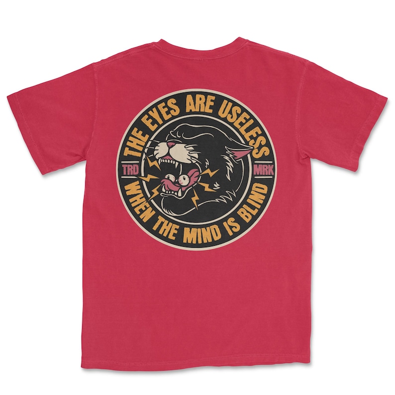 A traditional tattoo shirt featuring a panther with eyes in its mouth and the phrase “The eyes are useless when the mind is blind,” printed on a Comfort Colors tee for fans of tattoo art and alternative clothing.