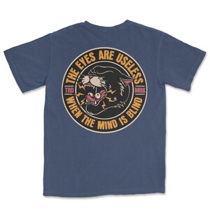 A traditional tattoo shirt featuring a panther with eyes in its mouth and the phrase “The eyes are useless when the mind is blind,” printed on a Comfort Colors tee for fans of tattoo art and alternative clothing.