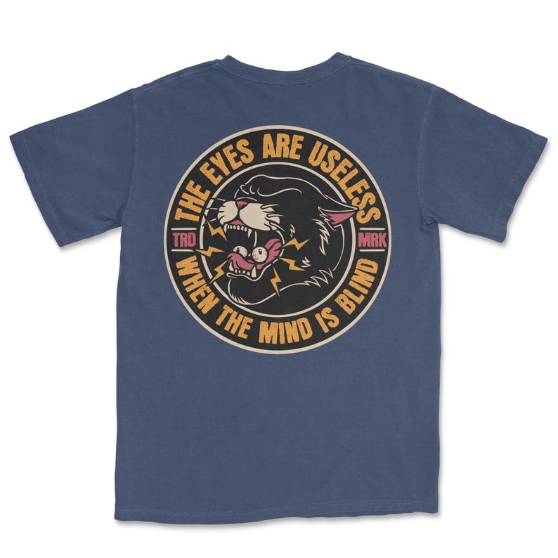 A traditional tattoo shirt featuring a panther with eyes in its mouth and the phrase “The eyes are useless when the mind is blind,” printed on a Comfort Colors tee for fans of tattoo art and alternative clothing.