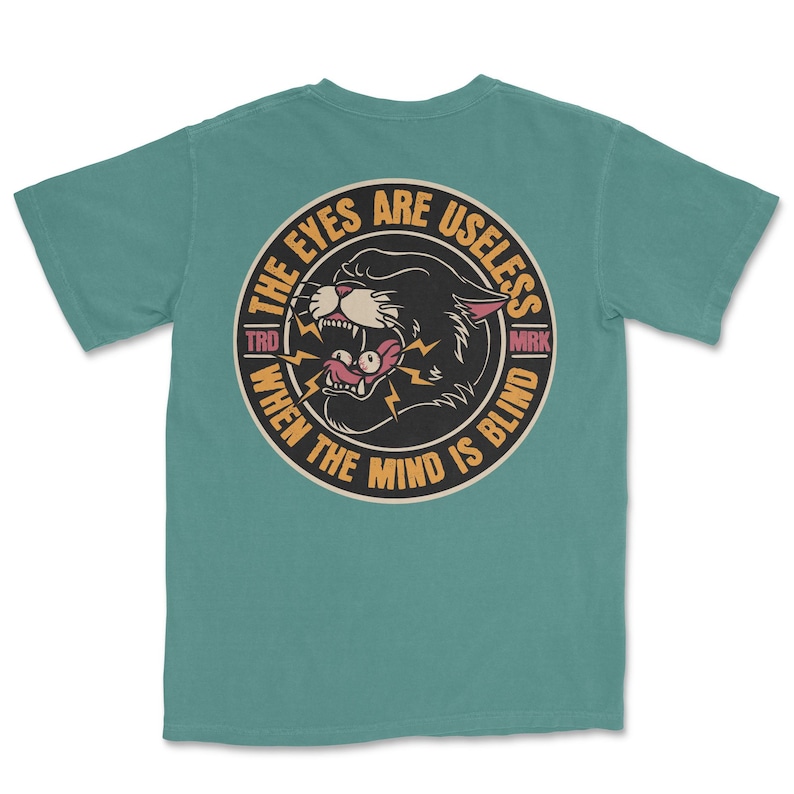 A traditional tattoo shirt featuring a panther with eyes in its mouth and the phrase “The eyes are useless when the mind is blind,” printed on a Comfort Colors tee for fans of tattoo art and alternative clothing.