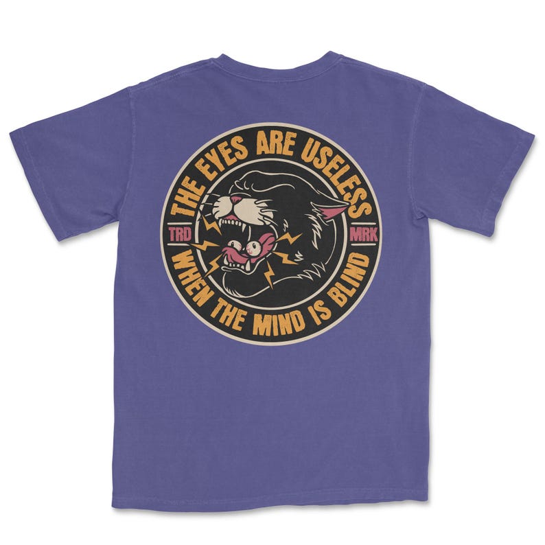 A traditional tattoo shirt featuring a panther with eyes in its mouth and the phrase “The eyes are useless when the mind is blind,” printed on a Comfort Colors tee for fans of tattoo art and alternative clothing.