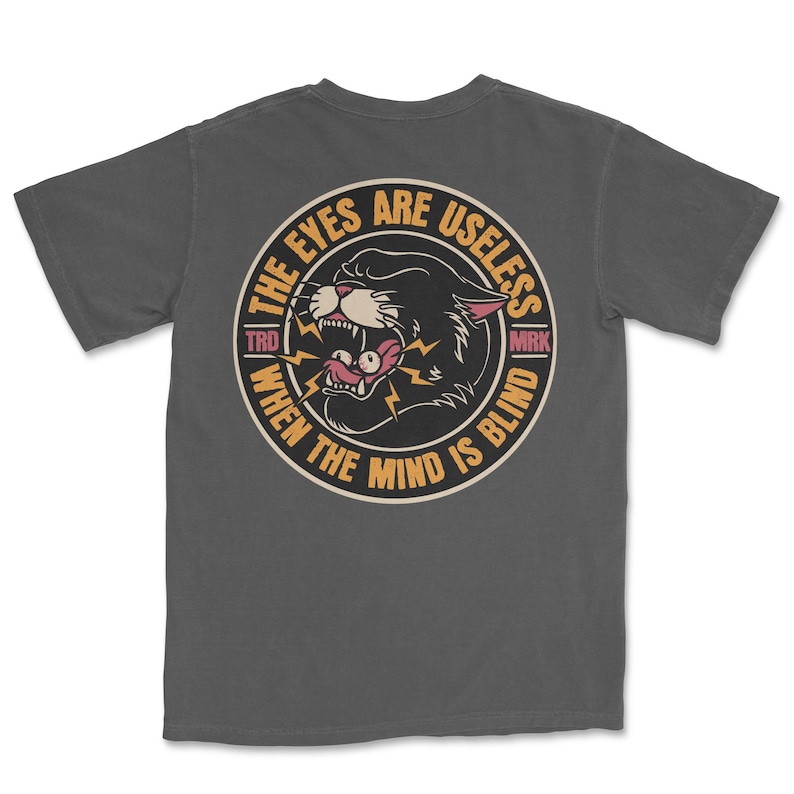 A traditional tattoo shirt featuring a panther with eyes in its mouth and the phrase “The eyes are useless when the mind is blind,” printed on a Comfort Colors tee for fans of tattoo art and alternative clothing.
