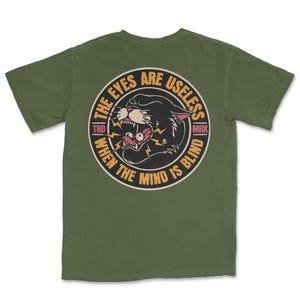 A traditional tattoo shirt featuring a panther with eyes in its mouth and the phrase “The eyes are useless when the mind is blind,” printed on a Comfort Colors tee for fans of tattoo art and alternative clothing.