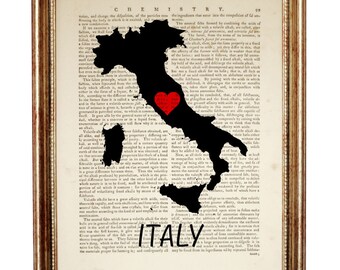 May include: A framed print featuring a black silhouette of the map of Italy overlaid on a vintage chemistry textbook page. A small red heart is positioned in the center of the map, and the word ITALY is printed in black capital letters below.