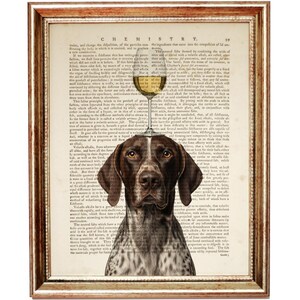May include: A framed print showing a German Shorthaired Pointer with a wine glass balanced on its head. The dog is set against a backdrop of vintage book pages with the word "CHEMISTRY" at the top. The frame is gold.