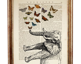May include: A framed wall art print featuring a black ink illustration of an elephant with its trunk raised toward a cluster of colorful butterflies, superimposed over a vintage dictionary page with the text CHEMISTRY at the top.