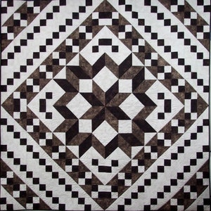 May include: A quilt with a geometric pattern of black and white squares and triangles. The center of the quilt features a large, eight-pointed star.