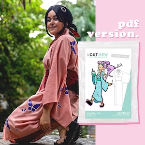 Può includere: Un kimono rosa con disegni di farfalle blu. L'immagine mostra anche un pacchetto di modelli con un'illustrazione a cartoni animati di una donna in kimono, che tiene in mano una bevanda e un cagnolino. Il testo sulla confezione recita "//CUT/SEW PATTERNMAKING".