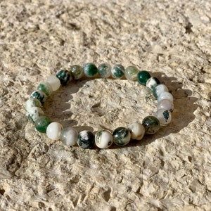 May include: A green and white agate beaded bracelet. The beads are round and have a natural, polished finish.