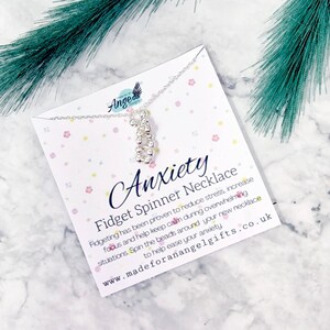 May include: Silver fidget spinner necklace with a card that reads "Anxiety Fidget Spinner Necklace" and includes information about the benefits of fidgeting. The card also includes the website address "www.madeforanangelgifts.co.uk".