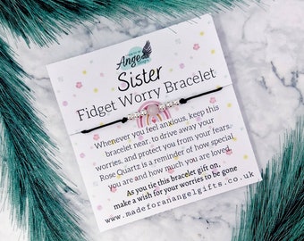 May include: A black string bracelet with a pink rose quartz bead and silver beads. The bracelet comes with a card that reads "Sister Fidget Worry Bracelet" and includes a message about the benefits of rose quartz. The card also includes the website address "www.madeforanangelgifts.co.uk".