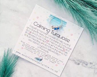 May include: A silver ring with turquoise blue beads. The ring is adjustable and comes with a card that says "Calming Turquoise" and describes the benefits of turquoise. The card also says "Fidgeting has been proven to help soothe and ease anxiety. Spin the calming Turquoise stone and it can induce internal serenity and lift depleted spirits. Not only will turquoise help to flush negative emotions from the mind, it is also said to support detoxification of the body."