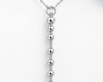 May include: A silver-toned necklace featuring a delicate chain and a vertical pendant composed of seven polished spherical beads arranged in a straight line, connected by thin metal rods, creating a clean and symmetrical linear design.