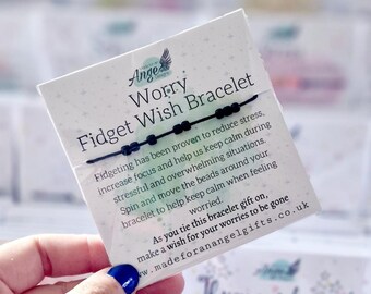 May include: A black string bracelet with five small black beads on a white display card. The card features the text "Worry Fidget Wish Bracelet" and instructions on how to use the beads to reduce stress and make a wish while tying the bracelet.