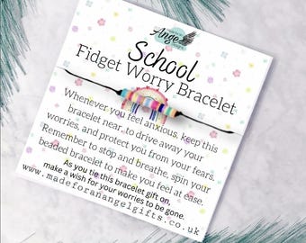 May include: A "School Fidget Worry Bracelet" on a white card with text and a beaded bracelet. The bracelet has rainbow-colored beads. The card has a floral pattern and the text "Ange Designs".
