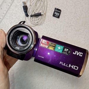 紫色のビデオカメラ JVC GZ-E100VU Everio、SD カード、動作状態、日本製光学系、40 倍光学ズーム、充電コード、データ コード、バッテリー