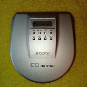 May include: A silver Sony CD Walkman portable CD player with a digital display showing "01:00:13". The player has buttons for "ESP", "Play Mode", "Replay/Enter", and "Sound".