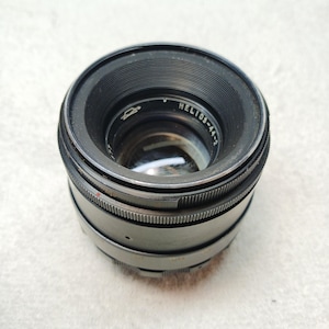 Peut inclure: Un objectif d'appareil photo noir Helios-44-2 avec des bagues de mise au point stri&eacute;es. L'objectif a un &eacute;l&eacute;ment en verre transparent et le texte "Helios-44-2" est visible sur le corps de l'objectif. L'objectif est con&ccedil;u pour la photographie.
