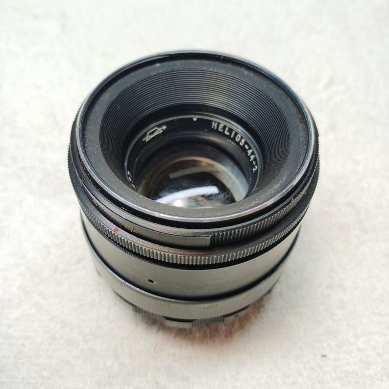 Peut inclure: Un objectif d'appareil photo noir Helios-44-2 avec des bagues de mise au point stri&eacute;es. L'objectif a un &eacute;l&eacute;ment en verre transparent et le texte "Helios-44-2" est visible sur le corps de l'objectif. L'objectif est con&ccedil;u pour la photographie.