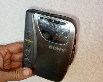 May include: A silver and black Sony Walkman cassette player with a digital tuner and a Mega Bass button. The player has a worn look and is slightly scratched.