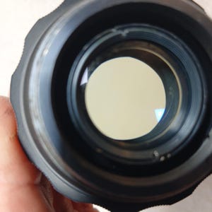 Peut inclure: Gros plan sur un objectif d'appareil photo noir avec un &eacute;l&eacute;ment en verre circulaire et clair au centre. L'objectif a un bord ext&eacute;rieur stri&eacute; et une surface int&eacute;rieure lisse et r&eacute;fl&eacute;chissante. L'image est ax&eacute;e sur l'int&eacute;rieur de l'objectif.