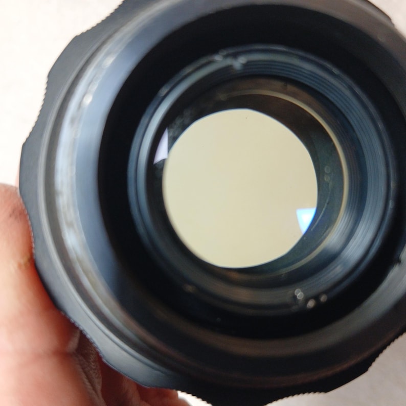 Peut inclure: Gros plan sur un objectif d'appareil photo noir avec un &eacute;l&eacute;ment en verre circulaire et clair au centre. L'objectif a un bord ext&eacute;rieur stri&eacute; et une surface int&eacute;rieure lisse et r&eacute;fl&eacute;chissante. L'image est ax&eacute;e sur l'int&eacute;rieur de l'objectif.