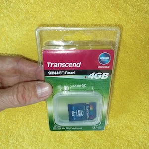 May include: A clear plastic package containing a Transcend 4GB SDHC Class 6 memory card. The card is blue and features the Transcend logo. The package also includes a lifetime warranty.