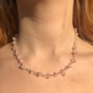 Puede incluir: Un delicado collar de cadena de plata con pequeñas piedras de cuarzo rosa claro.