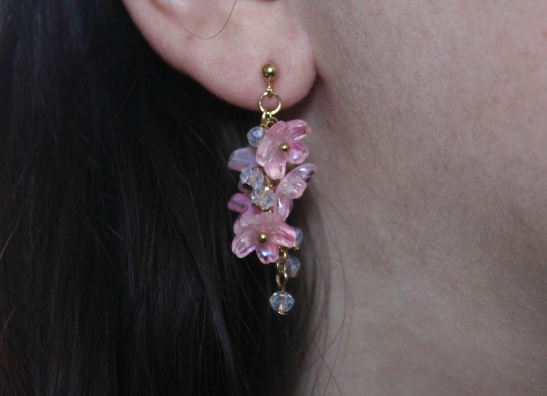 May include: Pink and purple flower dangle earrings with gold accents and crystal beads.