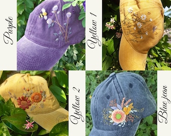 May include: Four embroidered baseball caps in different colors: purple, yellow, yellow, and blue jean. Each cap features a different floral design with embroidered details.