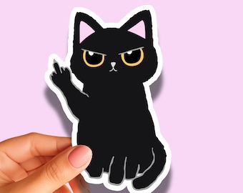 May include: A die-cut sticker featuring a black cat with large yellow eyes and pink inner ears. The cat has a grumpy expression and is holding up its right paw with the middle finger extended. The sticker has a white border and a matte finish.