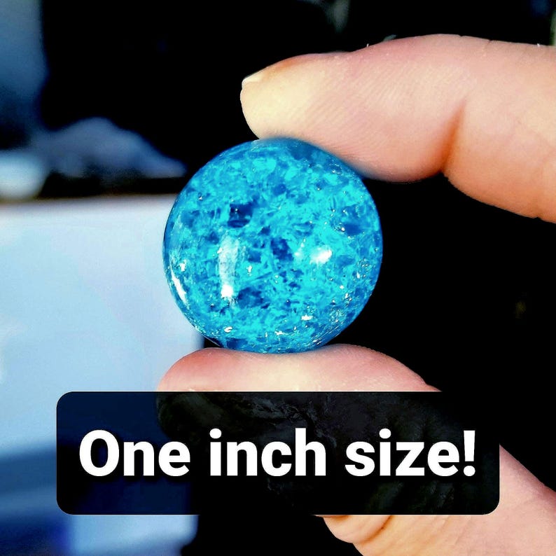 K&ouml;nnte beinhalten: Eine blaue Glaskugel mit einem Durchmesser von 2,5 cm und einem funkelnden, irisierenden Finish.