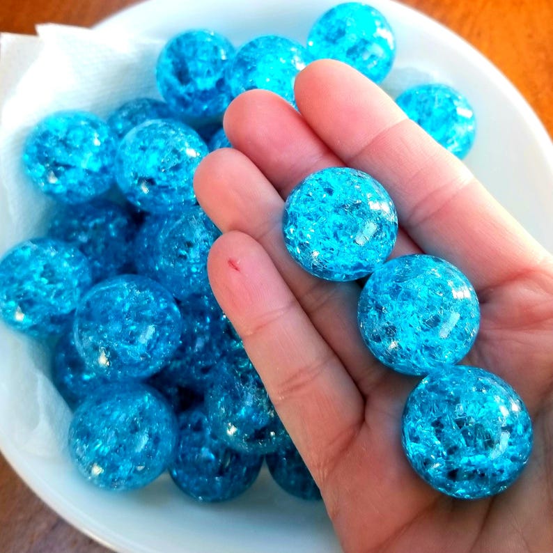 K&ouml;nnte beinhalten: Eine Schale gef&uuml;llt mit vielen kleinen, runden, blauen Glasmurmeln mit einem glitzernden, irisierenden Finish.