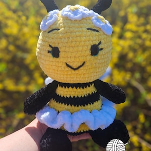 May include: A white ceramic mug with a black handle and the text "But First, Coffee" in a bold, black font. The mug is set against a blurred background, suggesting a cozy setting.