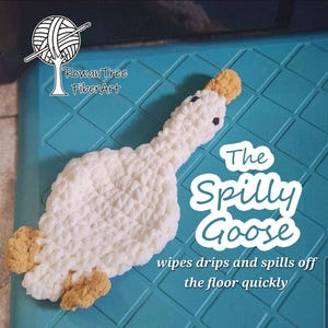 May include: A white crocheted goose with tan feet and a tan beak. The text on the image reads: RowanTree FiberArt, The Spilly Goose, wipes drips and spills off the floor quickly. The goose has two small black eyes and a textured yarn construction.