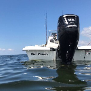 K&ouml;nnte beinhalten: Ein wei&szlig;es Boot mit einem schwarzen Au&szlig;enbordmotor mit der Aufschrift "Mercury 115" befindet sich im Wasser. Das Boot hat einen schwarzen Aufkleber mit der Aufschrift "Nauti Pleasure" an der Seite.
