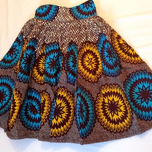 May include: A brown, yellow, and blue patterned skirt with a flared silhouette. The skirt has a circular design with a floral pattern.