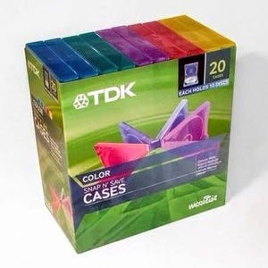 May include: A TDK brand box containing 20 colorful plastic snap n' save cases for storage. The packaging is green with text that reads TDK, COLOR SNAP N' SAVE CASES, and 20 CASES EACH HOLDS 10 DISCS. The top shows blue, green, purple, red, and yellow cases.