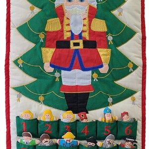 May include: A green felt advent calendar with 24 pockets, each containing a different embroidered figure. The calendar features a large embroidered Nutcracker figure at the top, with the text "The Nutcracker" above it.