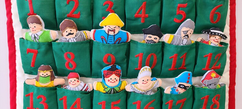 May include: A green felt advent calendar with 18 pockets, each featuring a different embroidered character and a red number. The characters are dressed in various costumes, including a pirate, a king, and a clown.