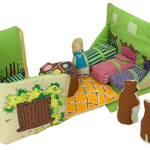 May include: A fabric playset depicting a house interior with a doll and bear figures. The set features green, yellow, and brown colours, with printed details of furniture and a window. Includes three beds, a doll, and three bear figures.