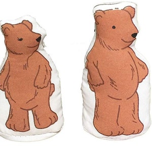 May include: A collection of four fabric dolls: a blonde girl in a blue dress, and three brown bears. The bears are of varying sizes, possibly representing a family. The dolls are made of white fabric with simple, cartoon-style illustrations.