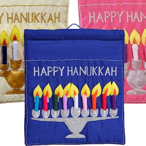 May include: A blue fabric banner with the text "Happy Hanukkah" in white embroidery. The banner features a menorah with nine candles, each with a different colored flame.