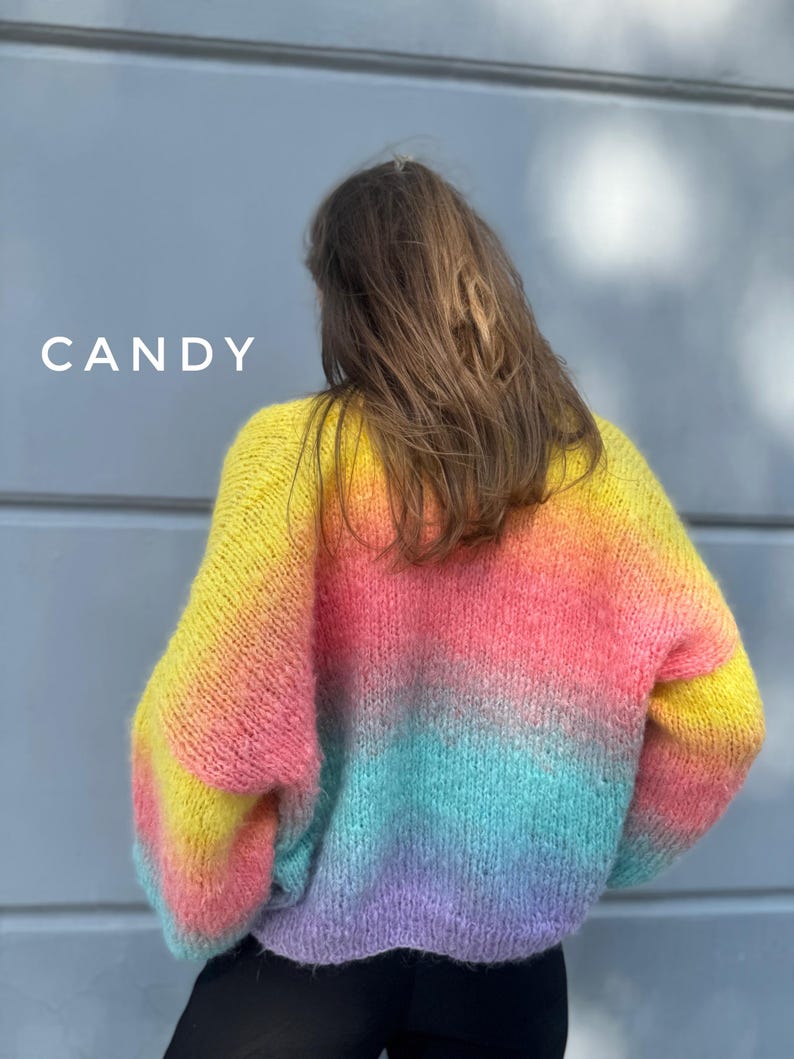 May include: A rainbow ombre knit sweater with a fluffy texture. The sweater is yellow, orange, pink, blue, and purple.