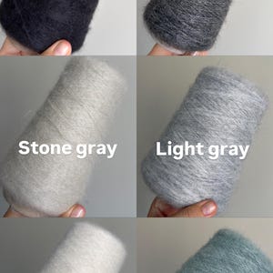Pu&ograve; includere: Sei coni di filato soffice in vari colori etichettati come Black, Dark gray, Stone gray, Light gray, White e Arctic. Ogni cono presenta un aspetto morbido, testurizzato e fibroso, mostrando una gamma di toni neutri e una tonalit&agrave; blu-verde.