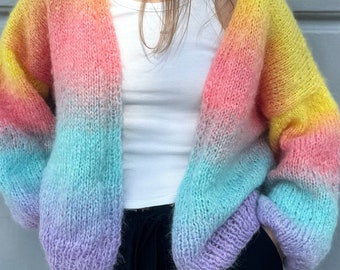 May include: A rainbow ombre cardigan with a loose fit and long sleeves. The cardigan is made of a soft, fuzzy yarn and has a relaxed, casual style.